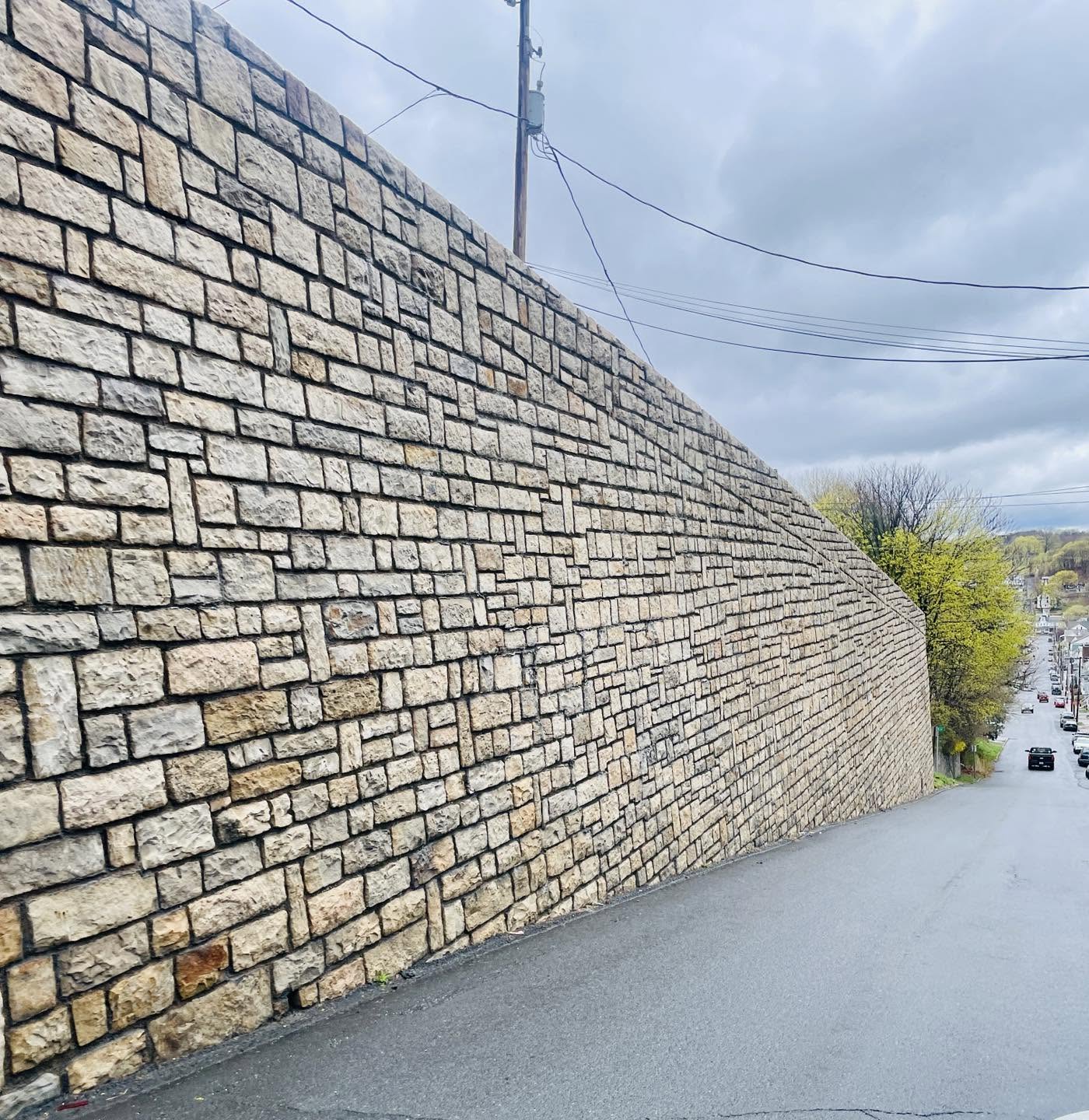 A large retaining wall of stacked stone, made from natural Pennsylvania sandstone, boarders a hill in Shamokin, PA.